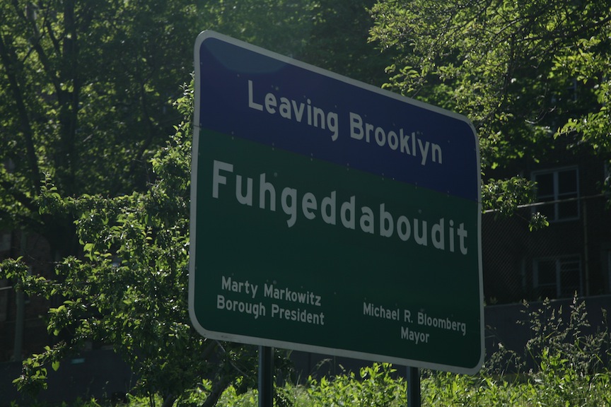 Il cartello stradale al confine tra Brooklyn e Queens sulla strada per l'aereoporto JFK: il cartello messo dal comune di NY, pensando di essere divertente, in realtà tocca un tasto per alcuni dolente dell'esperienza degli immigrati italiani in America