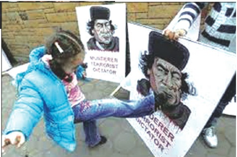 PRIMO PIANO/ Scrittura e società Nella foto una bambina libica prende a calci un manifesto con la foto di Gheddafi