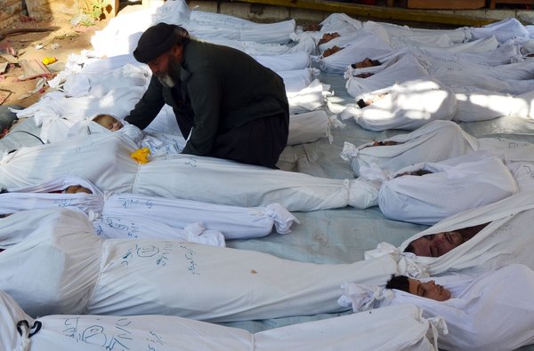 Attacco chimico in Siria, ma sapremo mai chi è stato? Un uomo compone il corpo di un bimbo tra tanti altri cadaveri vittime dell'attacco di ieri notte (Reuters)